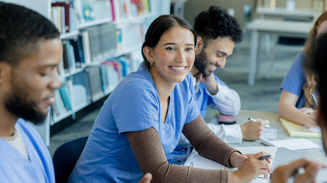 Physicians sitting together at a table with pens and paper.